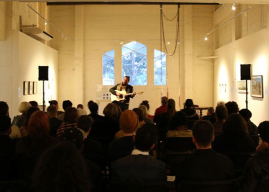 Person performing on guitar in Incinerator Gallery