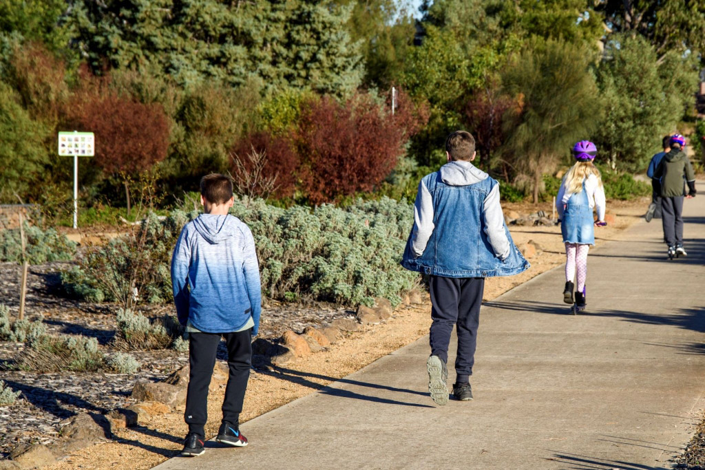 A group of young people walking and scooting at The Botanic Gardens