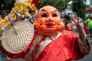 Person with large orange mask, doing peace sign, at the Lunar Festival in Brimbank