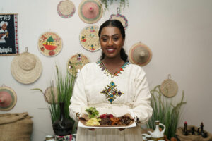 African woman in national dress smiling and holding plate of food