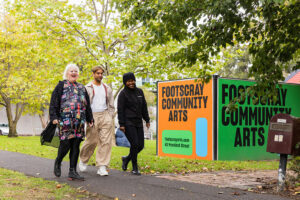 Three people walking in front of Footscray Community Arts center