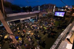 People in deckchairs watching movie on large outdoor screen