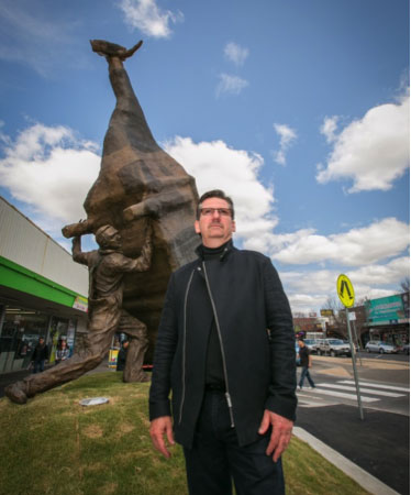 Artist John Kelly with sculpture 'Man Lifting Cow'