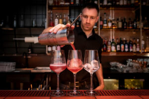 Bartender pouring cocktails into glasses